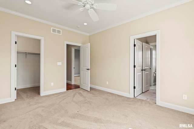 unfurnished bedroom with visible vents, crown molding, a spacious closet, and carpet flooring