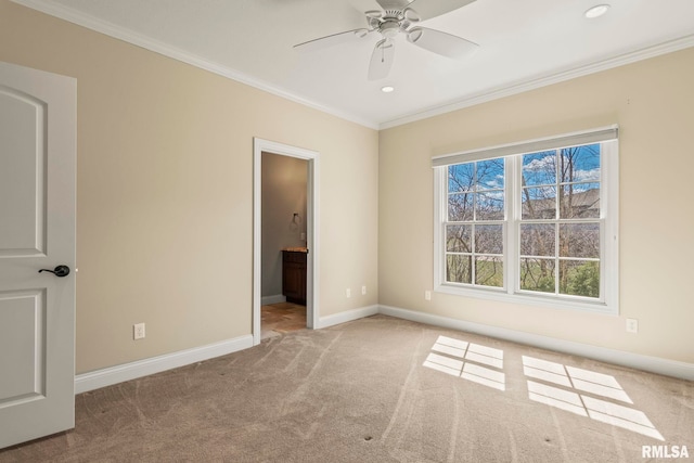 carpeted spare room featuring baseboards, ceiling fan, and crown molding