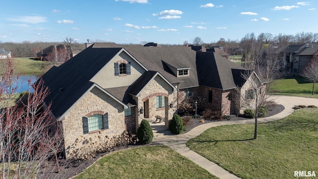 french country style house with stone siding, stucco siding, roof with shingles, and a front yard
