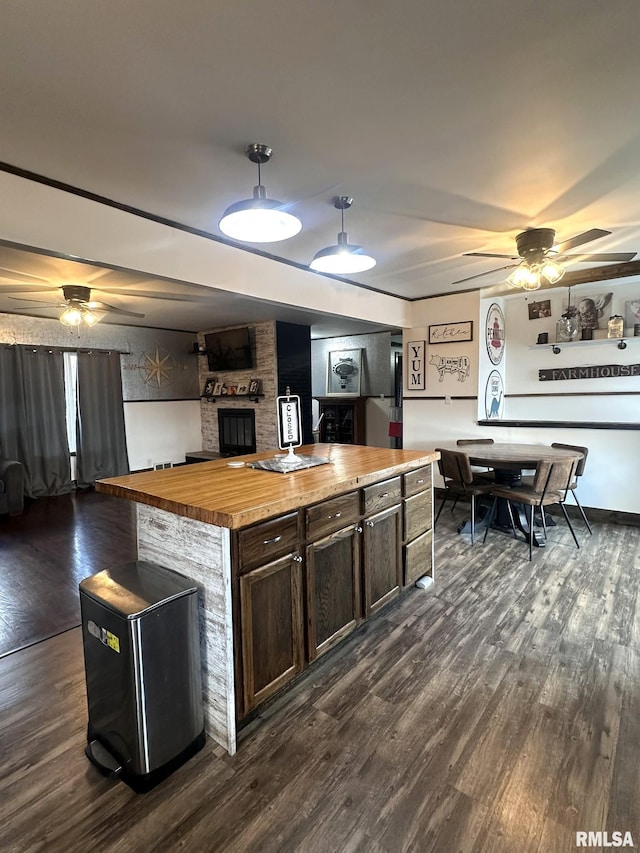 308 Galesburg Rd, Knoxville, IL 61448 - kitchen featuring wooden counters, ceiling fan, dark wood-type flooring, dark brown cabinetry, and a brick fireplace