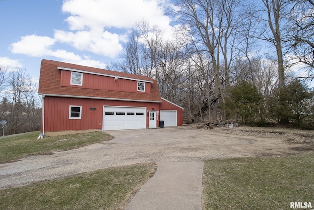 view of side of property with driveway, a shingled roof, and a detached garage