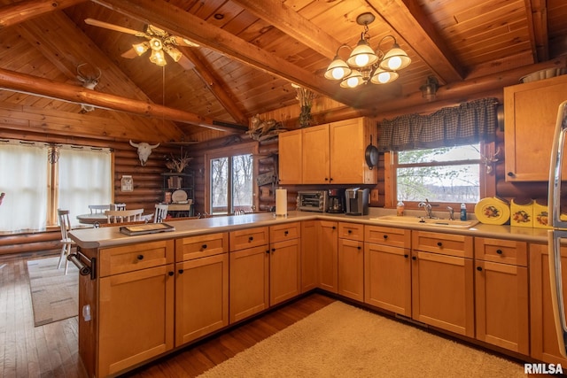kitchen featuring light countertops, a sink, a peninsula, and plenty of natural light