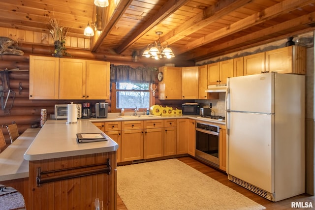 602 SE 13th St, Aledo, IL 61231 - kitchen featuring freestanding refrigerator, oven, rustic walls, a peninsula, and wood finished floors