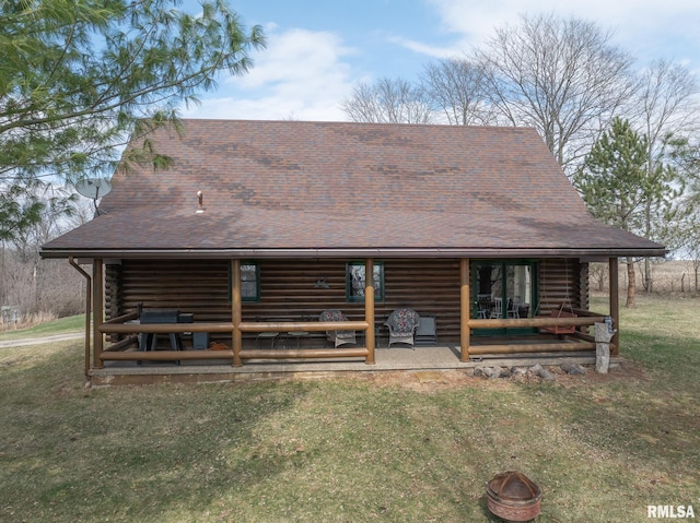 back of house with a fire pit, a shingled roof, a yard, and log exterior
