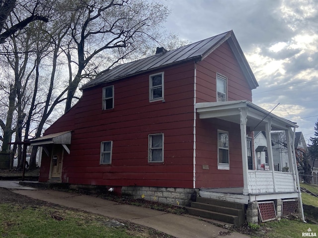 view of side of home featuring a porch, a standing seam roof, and metal roof