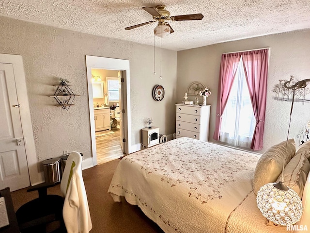bedroom with ensuite bath, a textured ceiling, a textured wall, and carpet floors