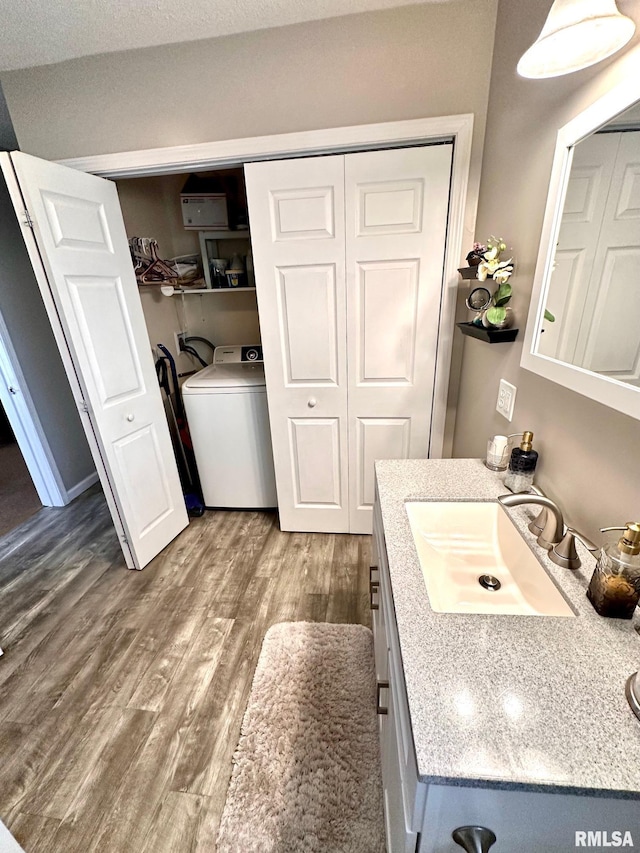 bathroom with washer / clothes dryer, wood finished floors, and vanity
