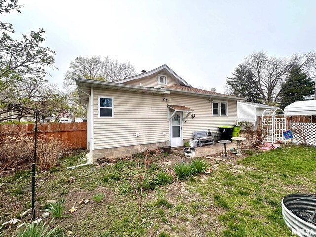 rear view of property with a lawn and fence