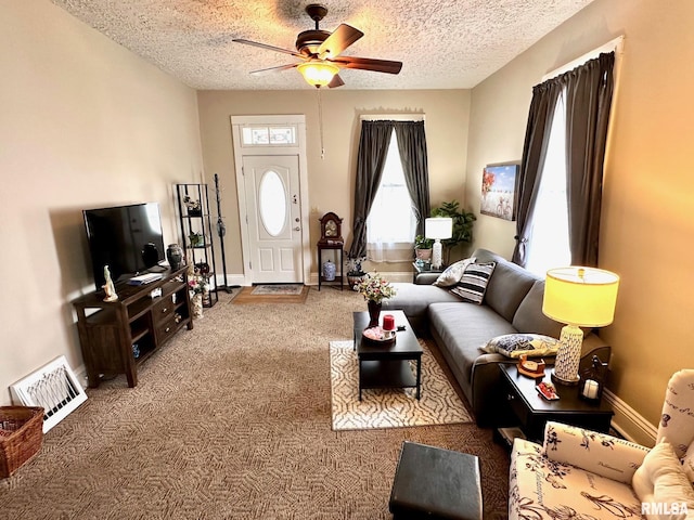 living area featuring baseboards, a textured ceiling, carpet floors, ceiling fan, and visible vents