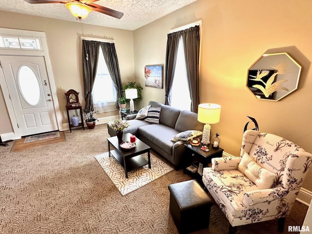 carpeted living room featuring baseboards, a textured ceiling, and a ceiling fan