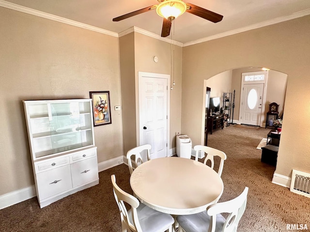 dining space with a ceiling fan, dark colored carpet, visible vents, arched walkways, and ornamental molding