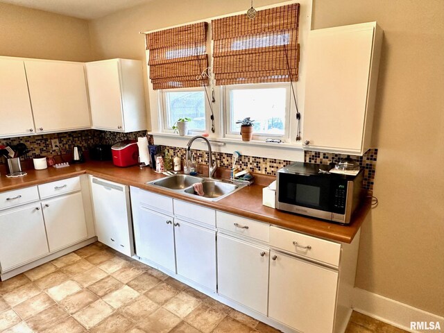 kitchen featuring stainless steel microwave, a sink, white dishwasher, and decorative backsplash