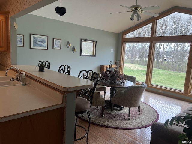 dining area featuring a ceiling fan, vaulted ceiling, and light wood-type flooring