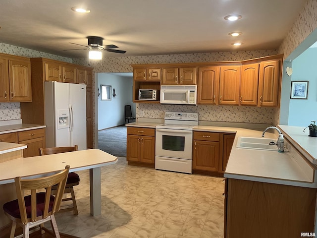 kitchen featuring wallpapered walls, a sink, and white appliances