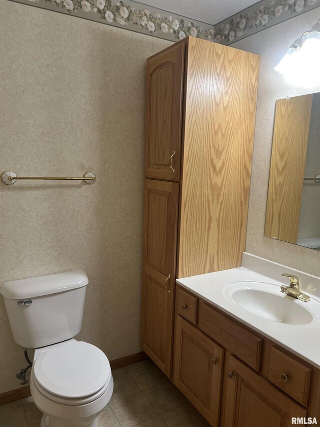 half bath with baseboards, toilet, tile patterned floors, and vanity