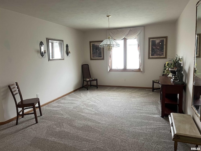 living area with baseboards, a notable chandelier, and carpet floors