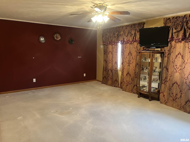 carpeted spare room featuring ornamental molding and a ceiling fan