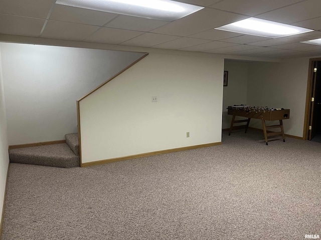 finished below grade area with baseboards, stairway, carpet flooring, and a drop ceiling