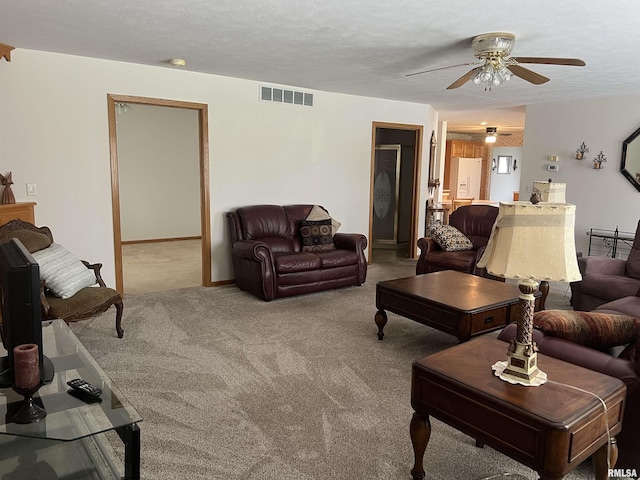 living area with a textured ceiling, visible vents, carpet floors, and a ceiling fan