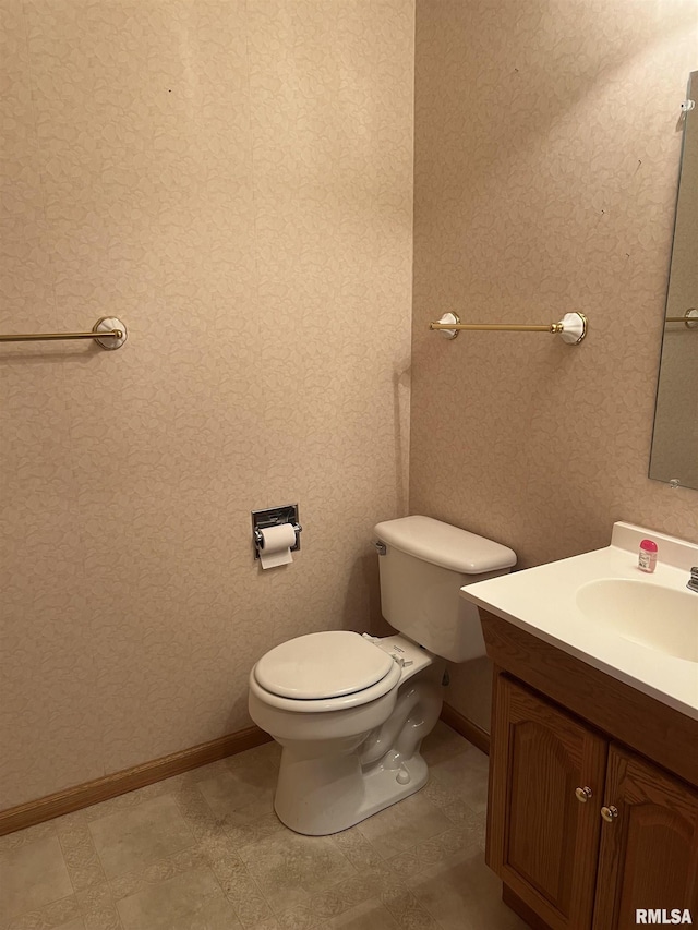 bathroom with toilet, vanity, and baseboards