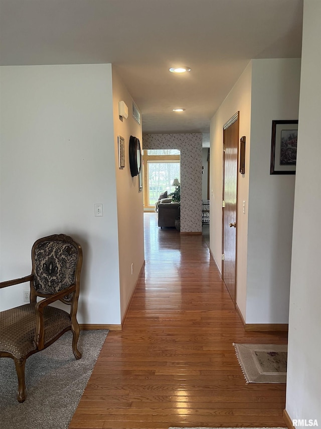 corridor with wallpapered walls, baseboards, and wood finished floors