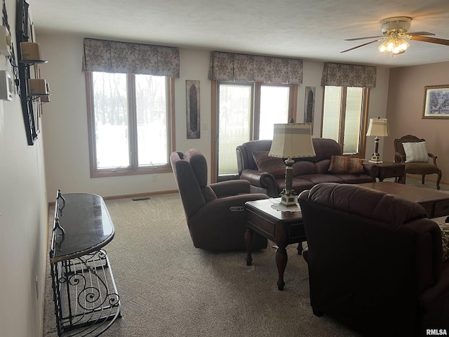 carpeted living room featuring baseboards, visible vents, and a ceiling fan