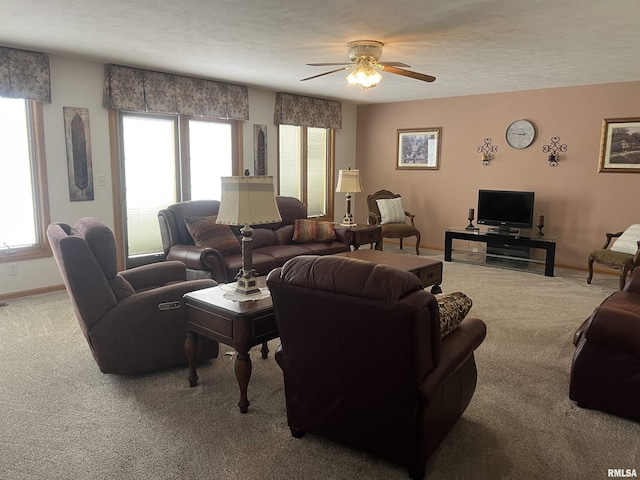 carpeted living area featuring baseboards, a textured ceiling, a wealth of natural light, and ceiling fan