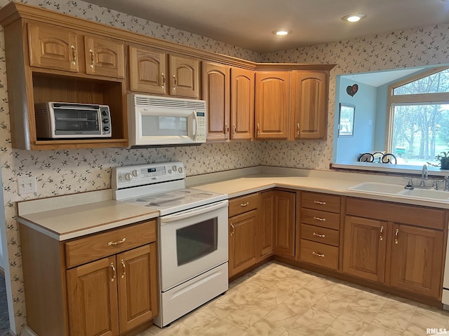 kitchen featuring light countertops, white appliances, a toaster, wallpapered walls, and a sink