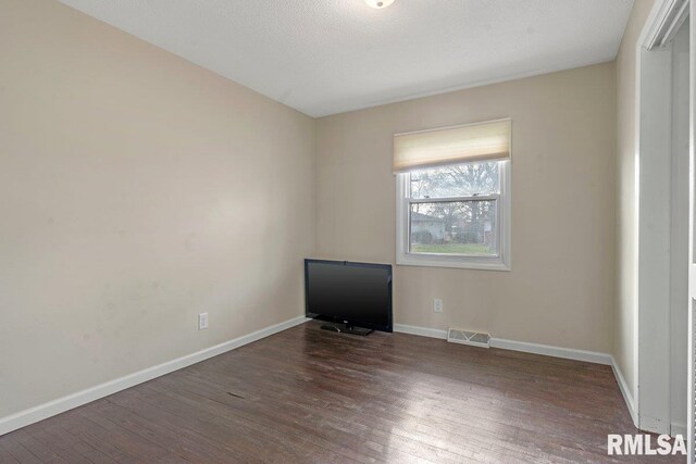 spare room featuring visible vents, baseboards, and wood finished floors