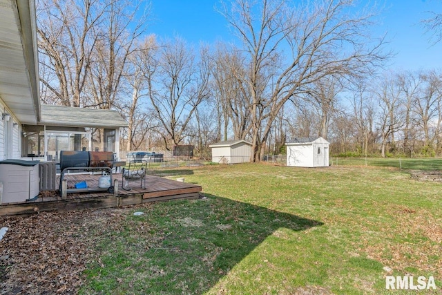 view of yard featuring an outbuilding, fence, a wooden deck, and a shed