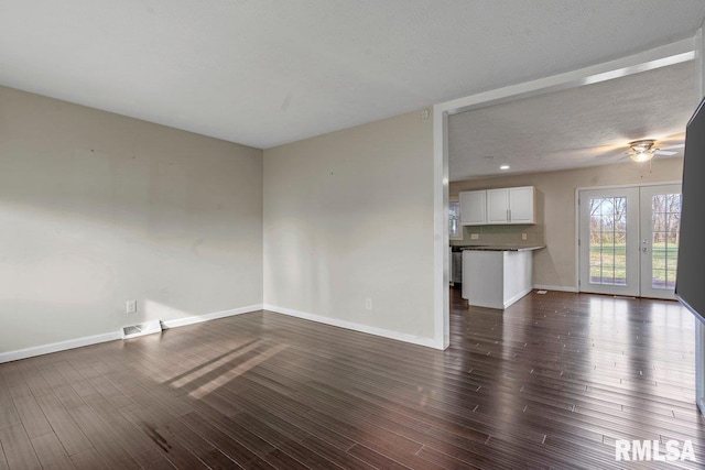 unfurnished living room with visible vents, baseboards, a ceiling fan, and dark wood-style floors