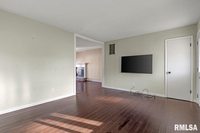 unfurnished living room featuring visible vents, baseboards, and wood finished floors