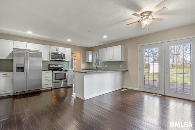 kitchen featuring tasteful backsplash, a sink, ceiling fan, white cabinetry, and stainless steel appliances