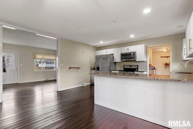 kitchen featuring white cabinetry, appliances with stainless steel finishes, a peninsula, and light stone countertops