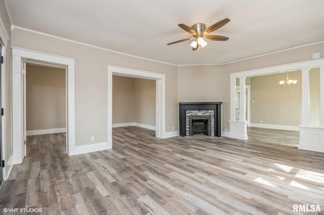 418 4th St, Illiopolis, IL 62539 - unfurnished living room featuring a fireplace, wood finished floors, ornamental molding, decorative columns, and ceiling fan with notable chandelier