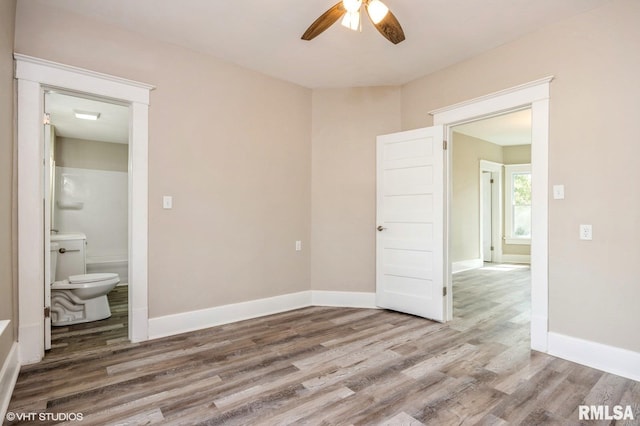 418 4th St, Illiopolis, IL 62539 - unfurnished bedroom featuring baseboards, wood finished floors, ensuite bath, and a ceiling fan