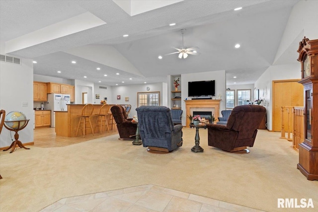 living area with visible vents, ceiling fan, a glass covered fireplace, and light carpet