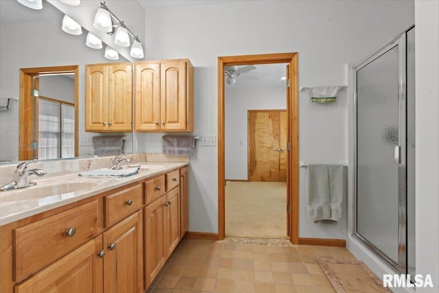 bathroom with baseboards, double vanity, a sink, and a shower stall