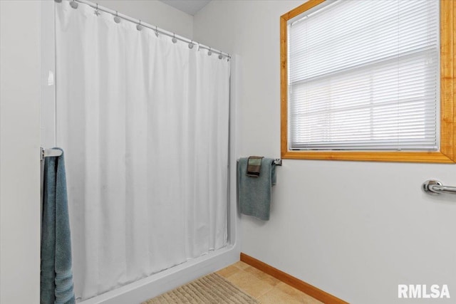 bathroom with a shower with curtain, tile patterned flooring, and baseboards