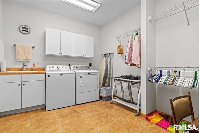 washroom featuring washer and dryer, cabinet space, a sink, and light tile patterned floors