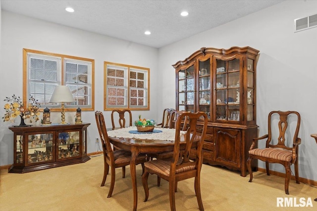 dining space featuring a textured ceiling, baseboards, light colored carpet, visible vents, and recessed lighting