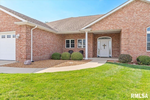 view of front of property featuring an attached garage, brick siding, roof with shingles, and a front yard