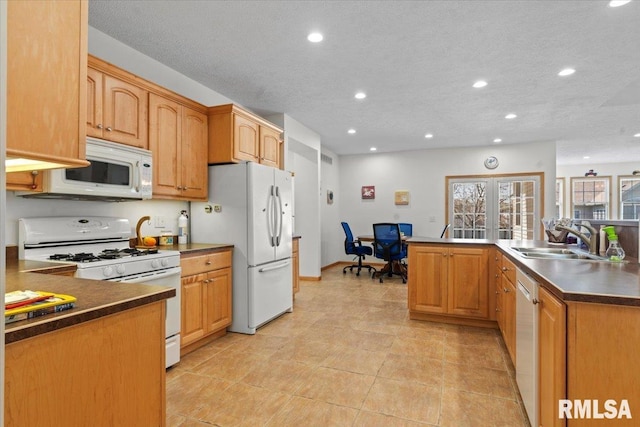 kitchen featuring a sink, dark countertops, recessed lighting, and white appliances