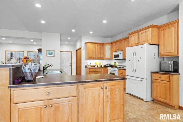 kitchen featuring a sink, dark countertops, recessed lighting, and white appliances