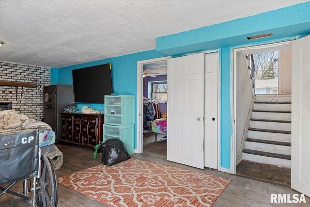 bedroom with multiple closets, a textured ceiling, wood finished floors, and multiple windows