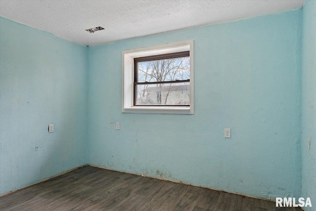 unfurnished room with a textured ceiling and wood finished floors