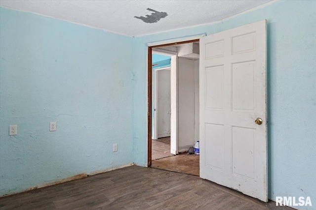 unfurnished bedroom with a textured wall, a textured ceiling, and wood finished floors