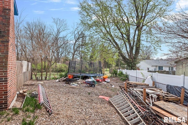 view of yard featuring a trampoline and a fenced backyard