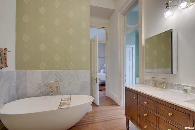 1477 Maine St, Quincy, IL 62301 - ensuite bathroom with double vanity, wood finished floors, wallpapered walls, a sink, and a freestanding bath
