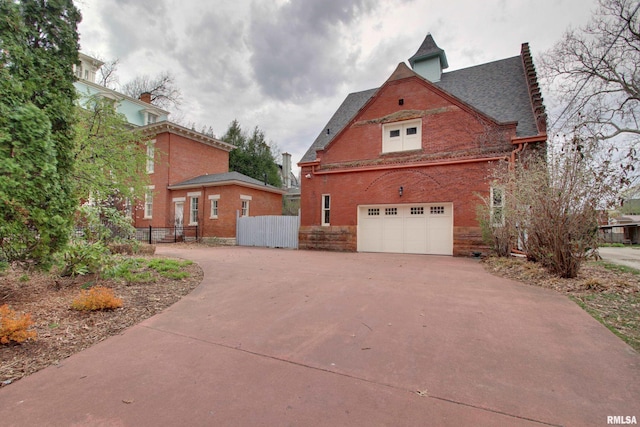 1477 Maine St, Quincy, IL 62301 - view of side of property featuring brick siding, concrete driveway, a garage, and fence